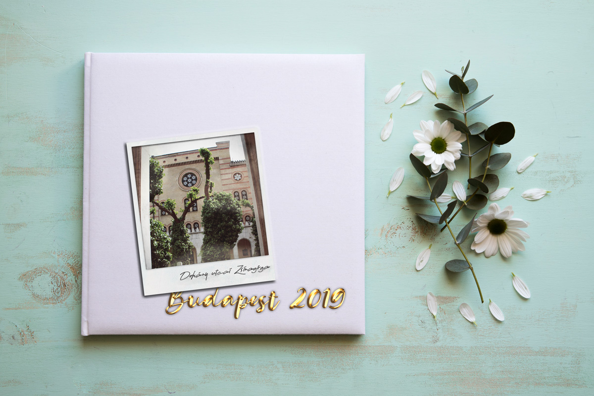 Polaroid-Foto der Dohany Synagoge auf einem weißem Fotoalbum, welches mit goldener Schrift auf den Budapest-Urlaub 2019 hinweist, dazu ein paar Blümchen am Rand.