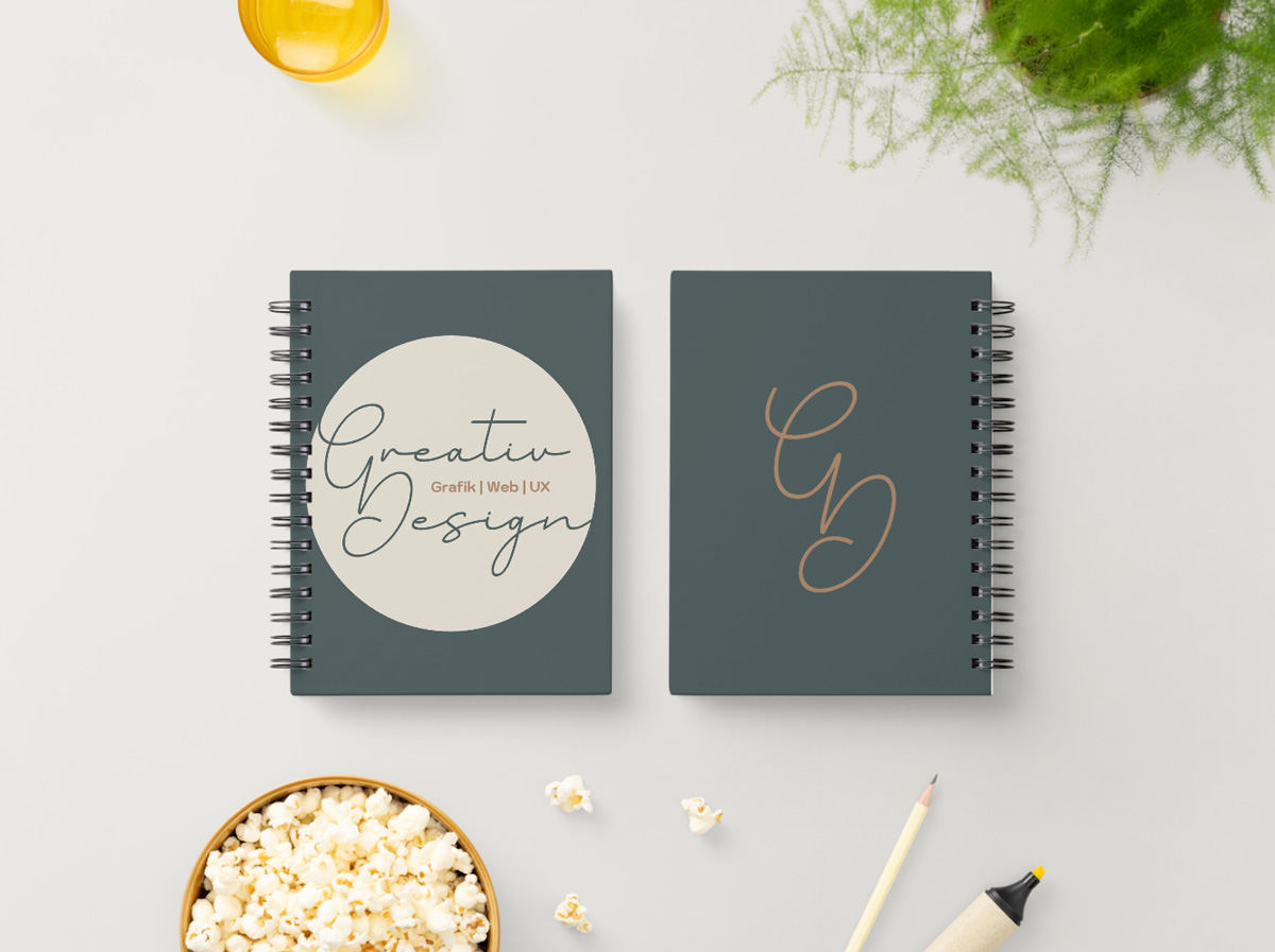 Zwei gebrandete Notizbücher mit dem Logo 'Greativ Design' – Kombination aus Handschrift und Serifentypo für einen persönlichen Markenauftritt.